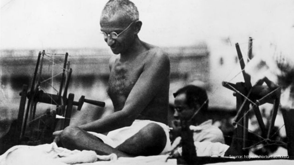 Mahatma Gandhi actively engaged with a spinning wheel during a 'Charlea'.